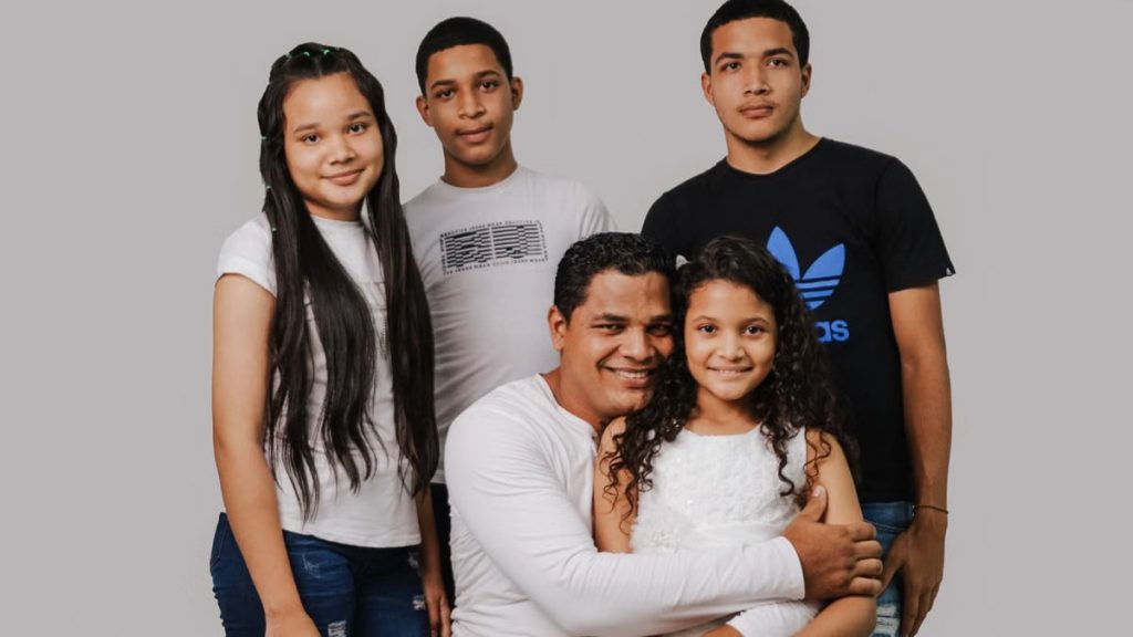 A father with his four children smiling warmly, depicting family love and togetherness.